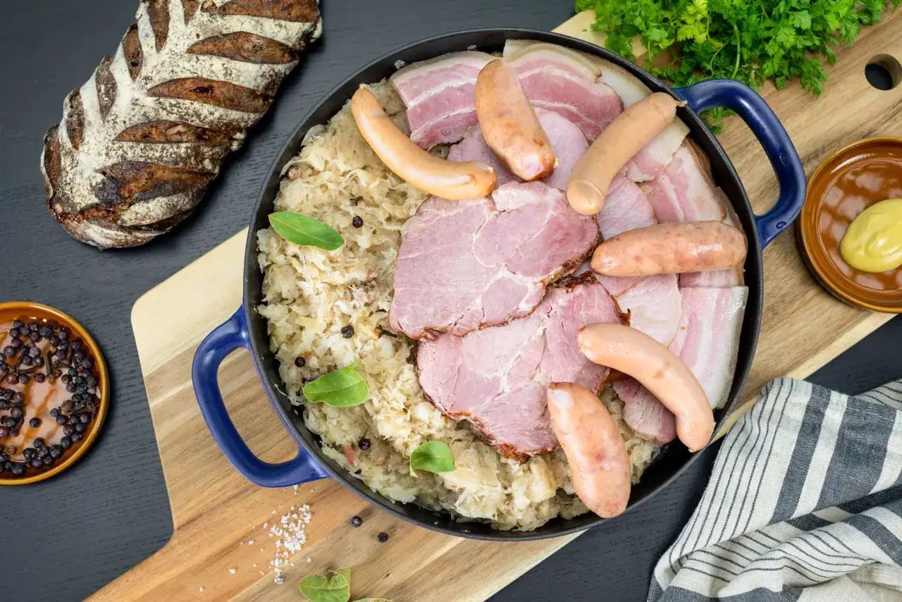 Un plat généreux de choucroute de Noël, garni de saucisses, jambon et lard, accompagné d'une miche de pain rustique.