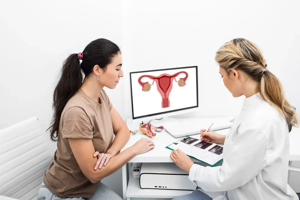 Lekarka wyjaśnia pacjentce, co to jest endometrium, pokazując schemat narządów rodnych na monitorze.