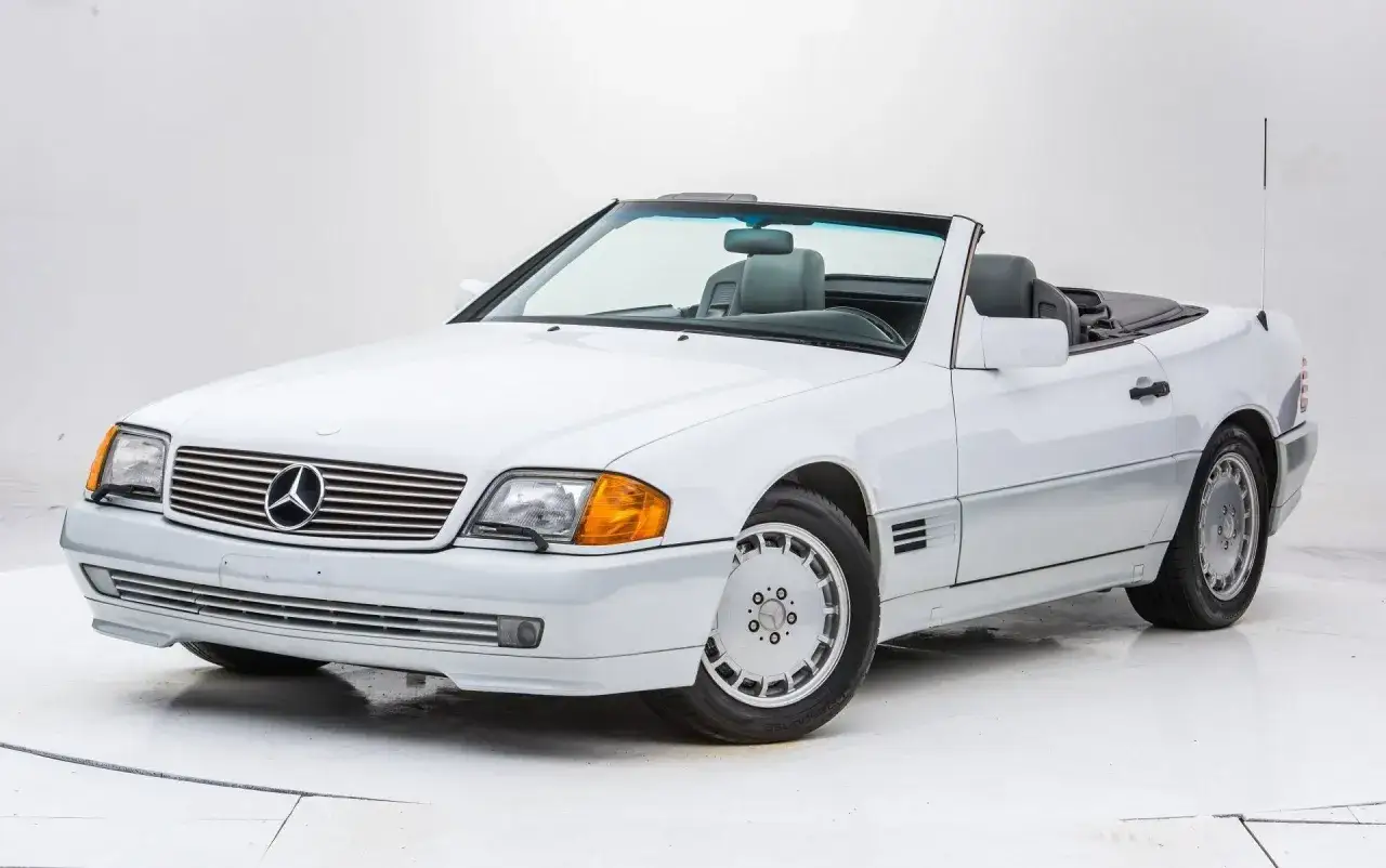 Biały kabriolet Mercedes-Benz SL500 z lat 90. z opuszczonym dachem, gotowy na letnią przejażdżkę.