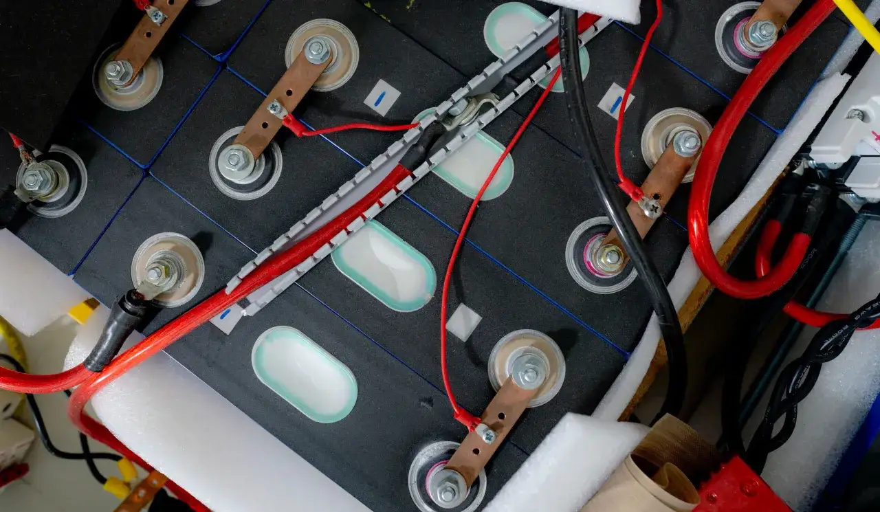 Zestaw ogniw tworzących baterię do samochodu elektrycznego, połączonych miedzianymi listwami i przewodami.