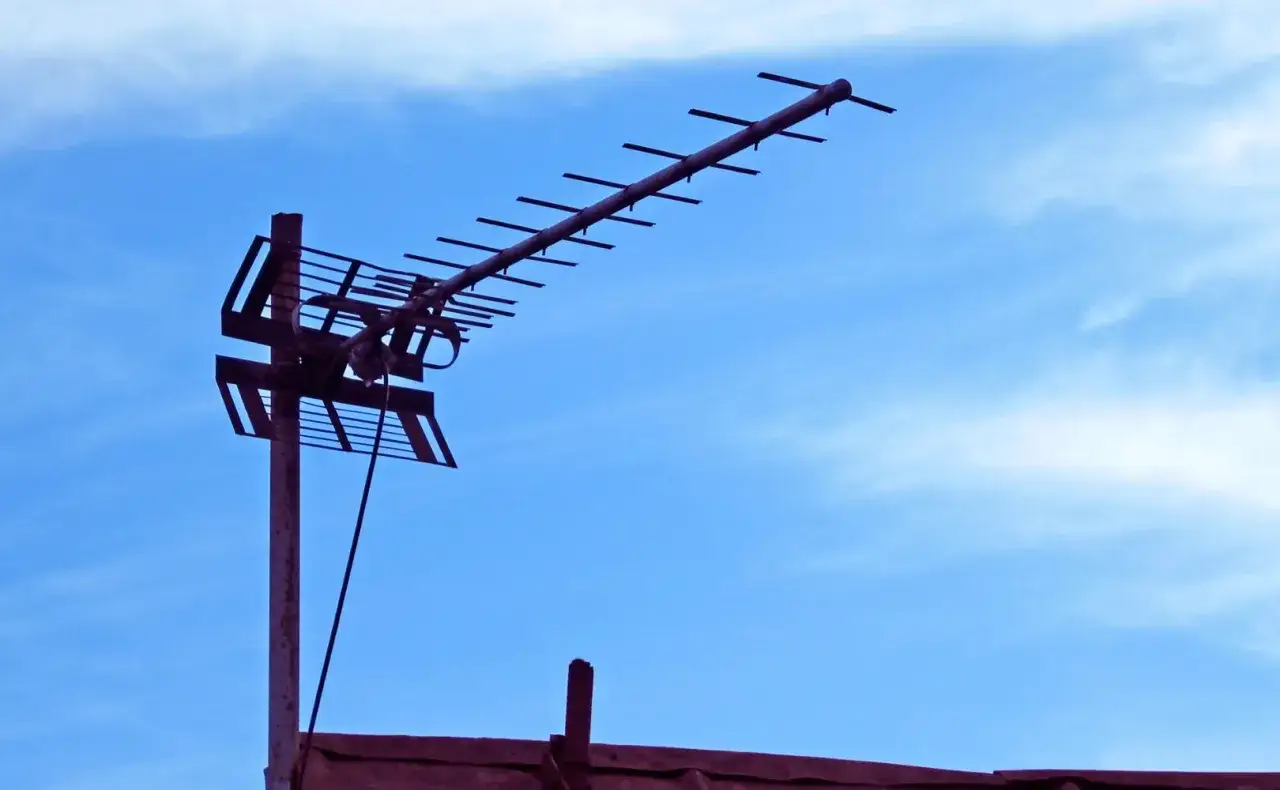 Antena naziemna do odbioru sygnału DVB-T na tle błękitnego nieba z chmurami.