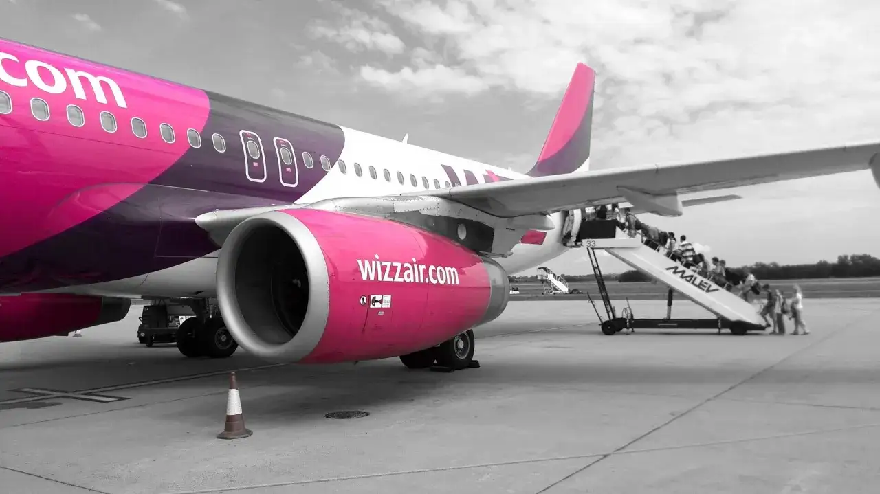 Samolot Wizz Air z pasażerami wchodzącymi po schodkach.