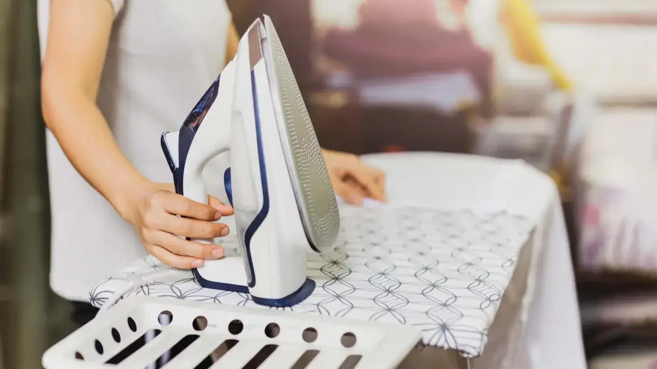 Persona plancha un vestido de satén con cuidado en una tabla de planchar.