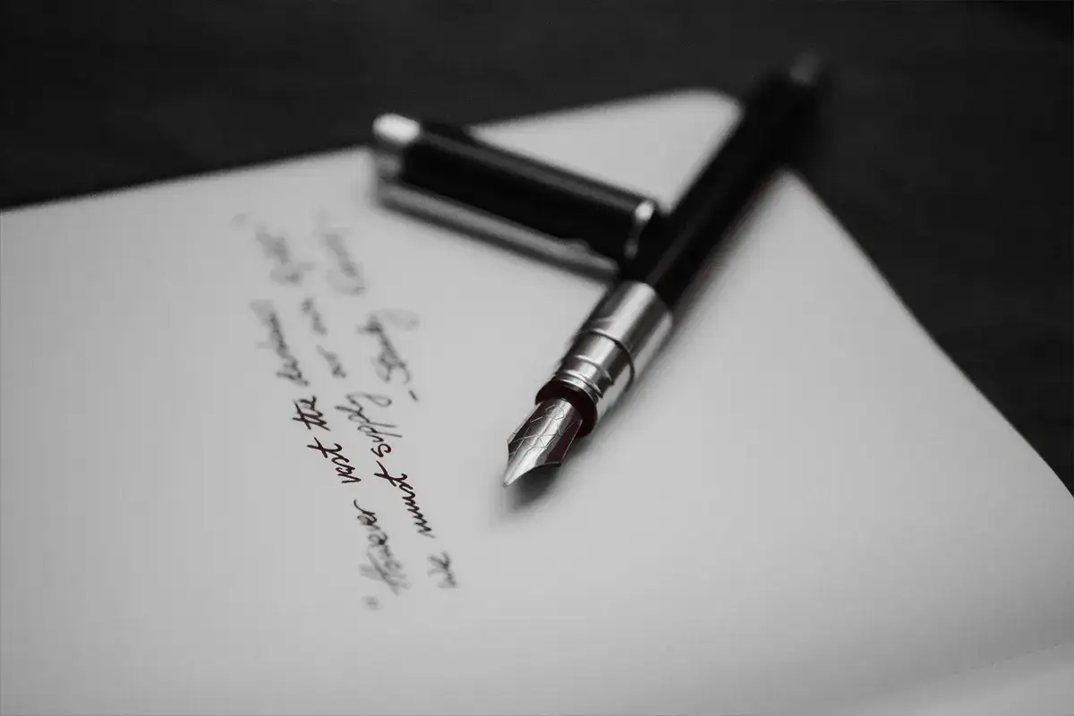 Pióro wieczne na papierze, gdzie widnieje fragment tekstu, być może ostatnia wola lub testament.