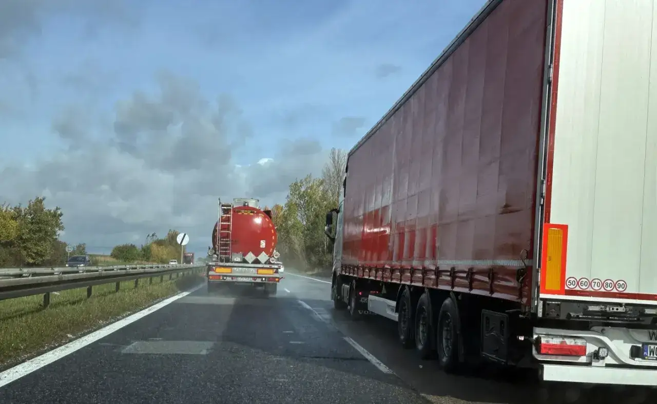 Ciężarówki jadą autostradą. Czy ciężarówki mogą wyprzedzać na autostradzie? Jedna z nich to cysterna, druga to naczepa.