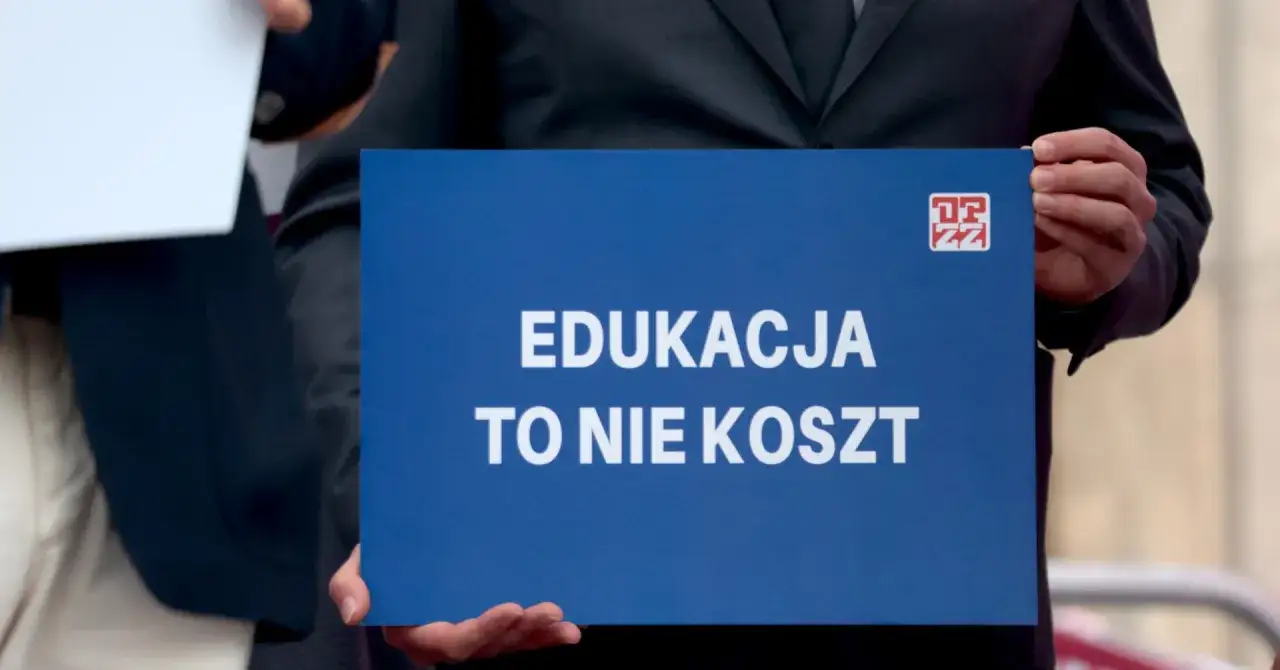 Nauczyciele domagają się podwyżek, trzymając transparent "Edukacja to nie koszt".