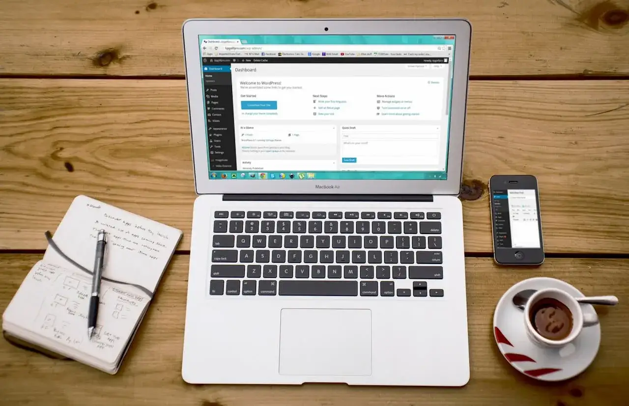 Na laptopie widać panel WordPress, obok smartfon i notatnik. To idealne miejsce do nauki, jak zainstalować WordPress na XAMPP.