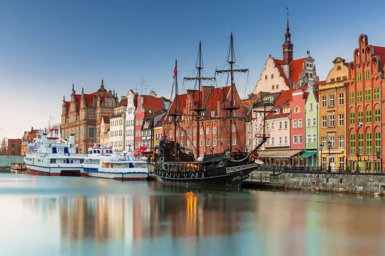 Gdański port z żaglowcem i kolorowymi kamienicami. To miejsce, co warto zwiedzić w Polsce, zachwyca historią i widokami.