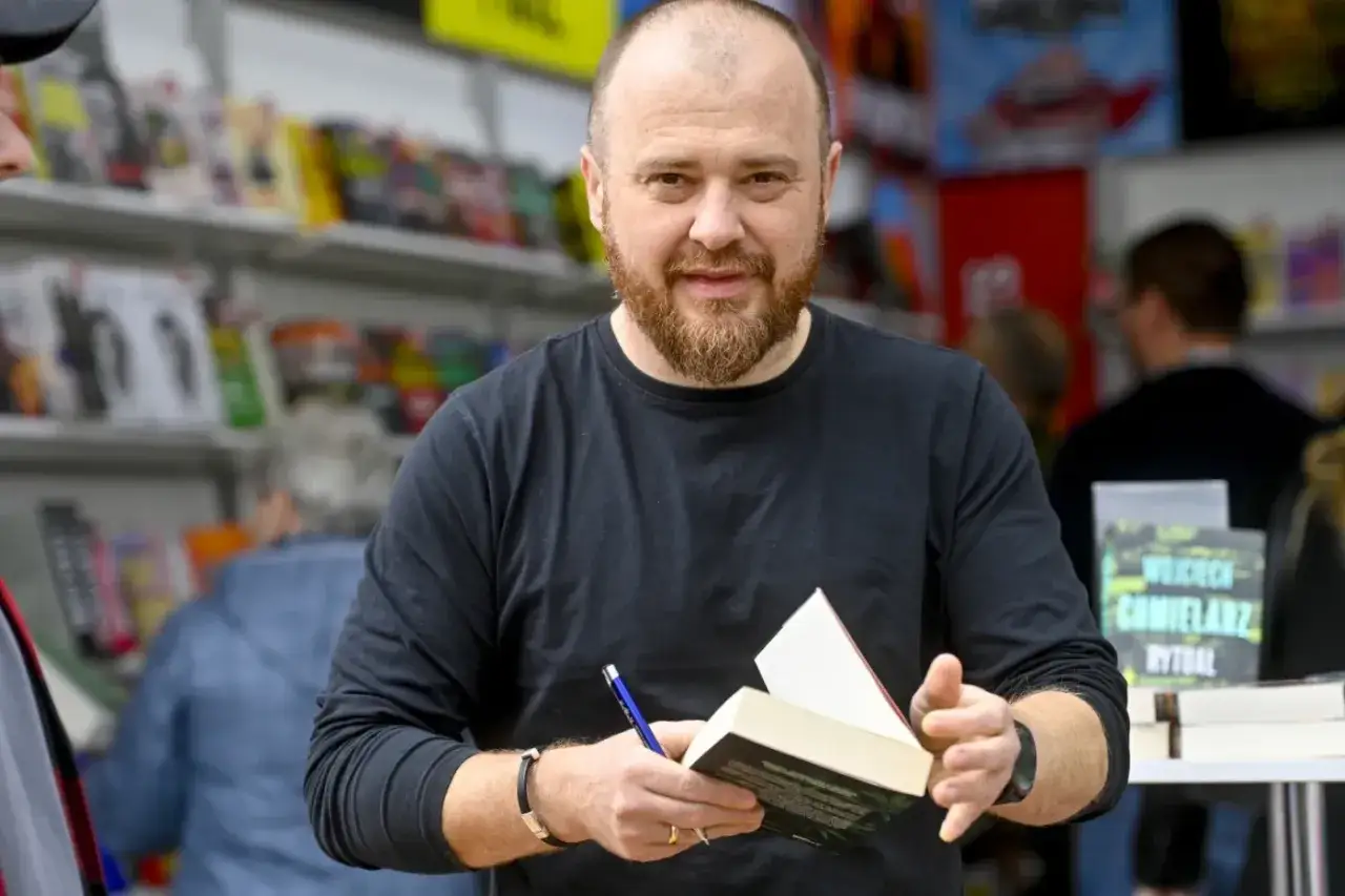 Chmielarz cykl gliwicki. Autor z książką i długopisem, w tle regały z publikacjami.