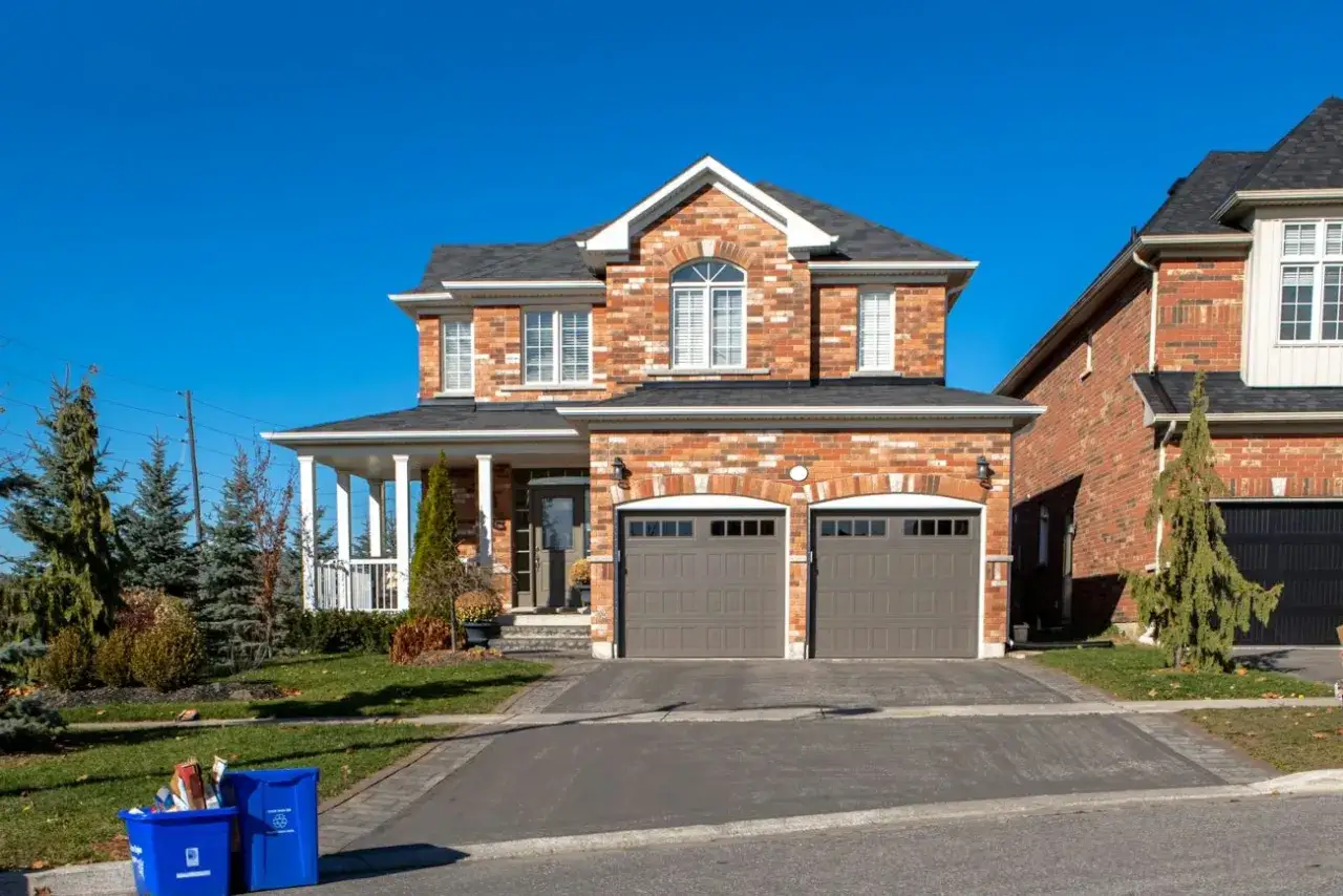 Elewacja frontowa definicja: dwupiętrowy dom z cegły z dwoma garażami, werandą i zadbanym ogrodem.
