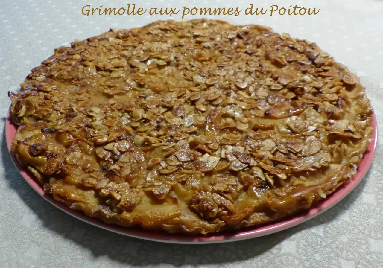 Gâteau rustique aux pommes et amandes effilées sur une assiette rose.
