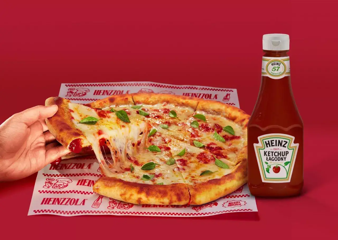 Ciepła pizza z ciągnącym serem i bazylią, obok butelka łagodnego ketchupu Heinz – idealny duet do każdego kęsa.