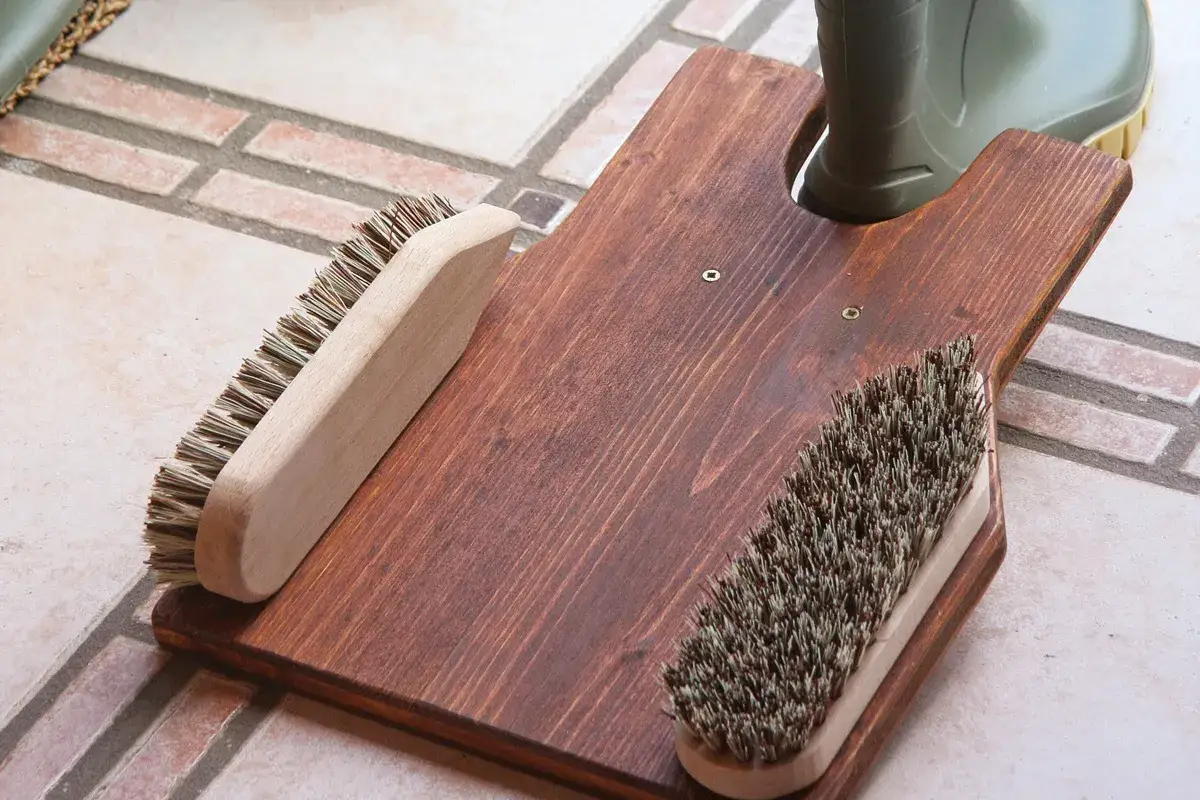 Selbstgebauter Bootsanker aus Holz mit zwei Bürsten und einem grünen Stiefel.