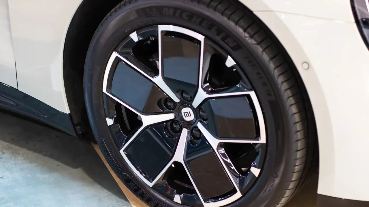 Pneu Michelin sur jante noire et argentée avec logo Mi sur une voiture blanche.