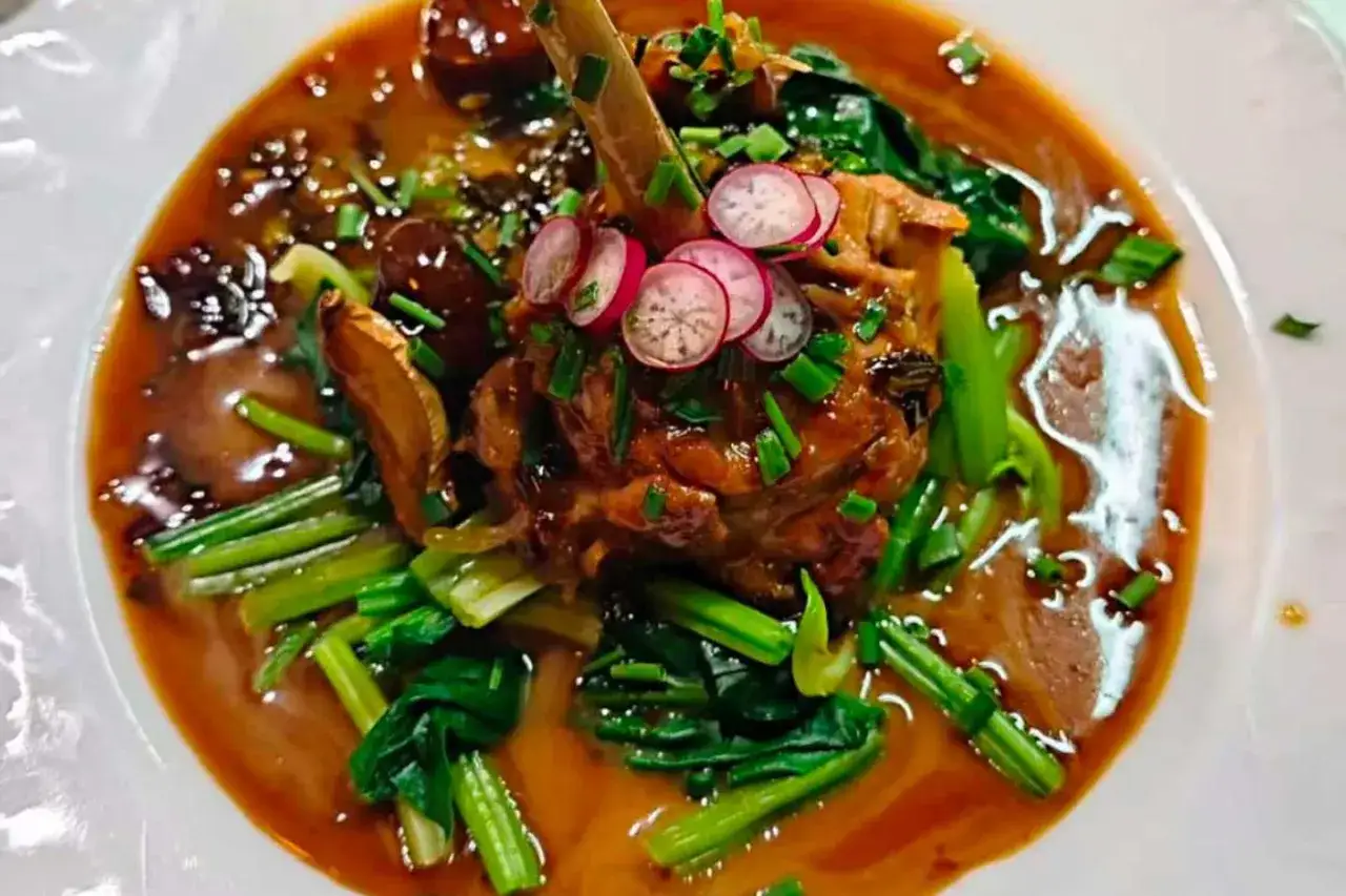 Un plat savoureux, un os de viande braisé dans une sauce riche, garni de radis et de légumes verts. Un aperçu des spécialités parisiennes.