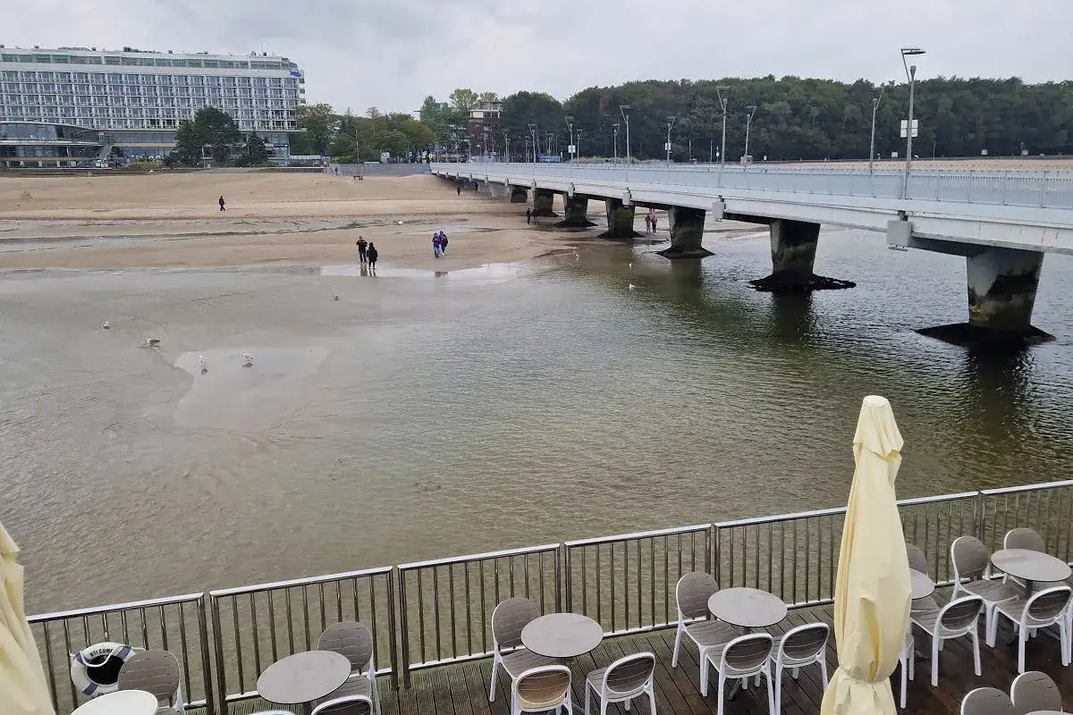 Spacerem po plaży, gdzie widać, kiedy przypływ kiedy odpływ. W oddali hotel i molo.