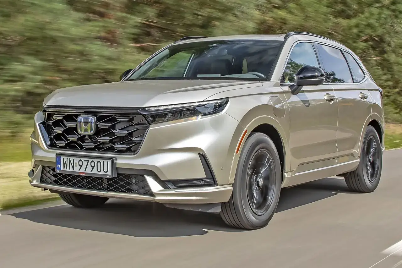 Złoty Honda CR-V Hybrid w ruchu, z widocznym grillem i światłami LED.