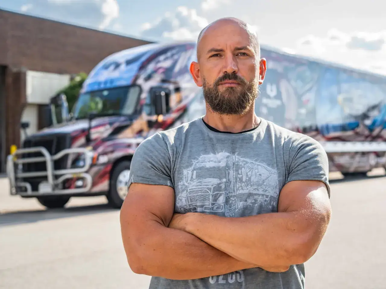 Dawid Andres, w sile wieku, z brodą, stoi przed ozdobioną ciężarówką.