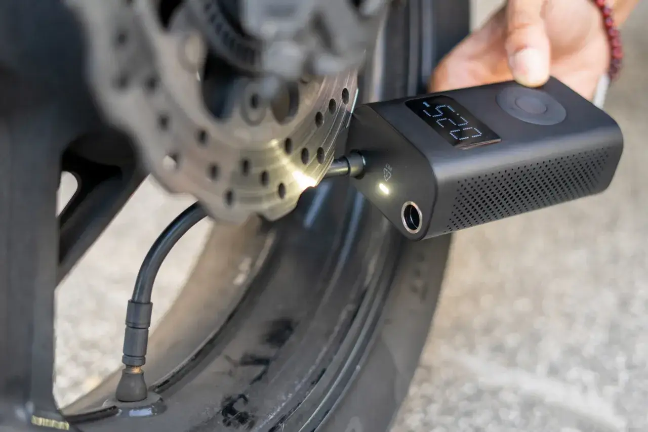 Gonfleur de pneu sans fil connecté à la valve d'une roue de moto, affichant la pression.