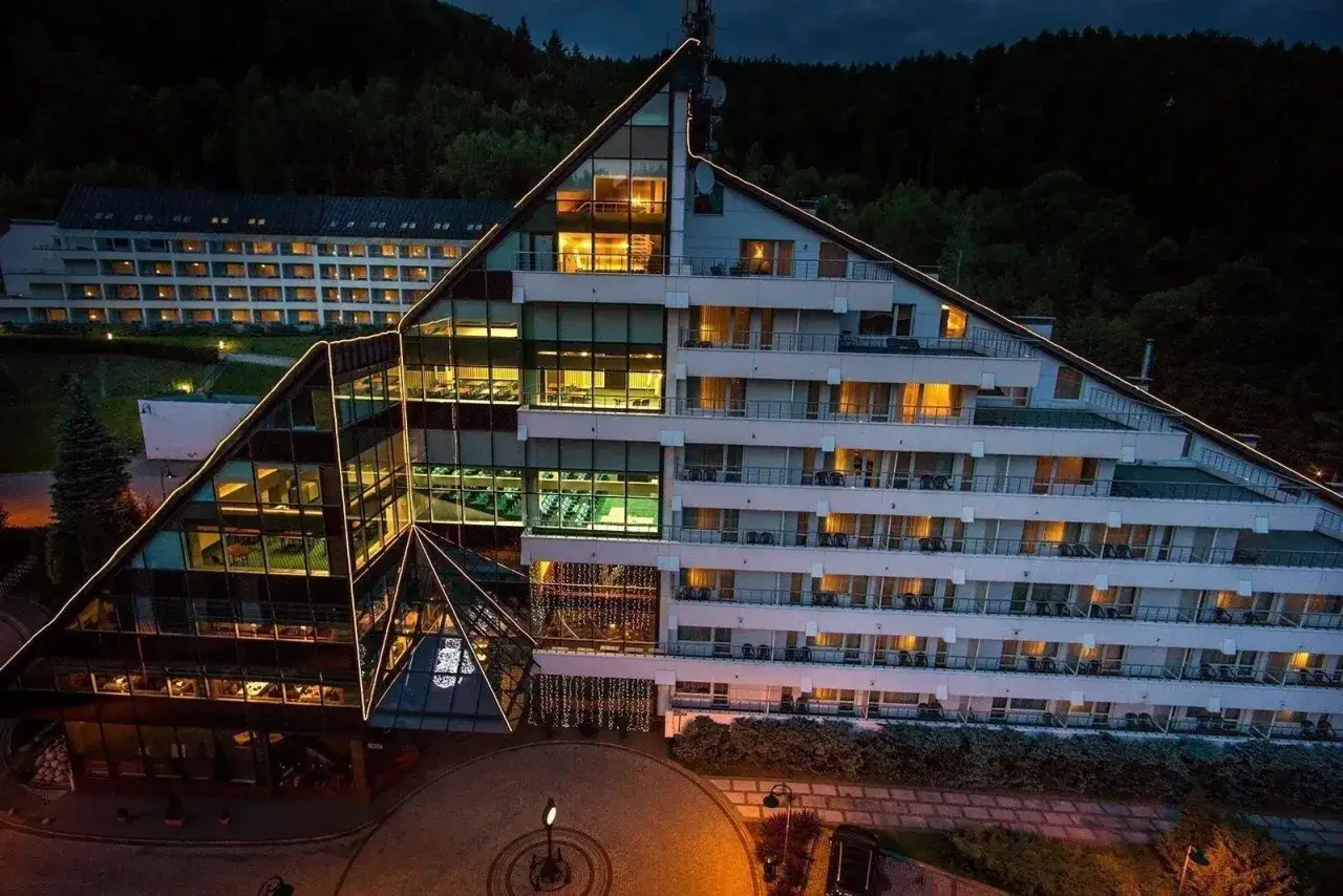 Nowoczesny hotel Klimczok Resort & Spa nocą, z oświetlonymi oknami i wejściem. Wiele pozytywnych hotel klimczok resort & spa opinie potwierdza jego urok.