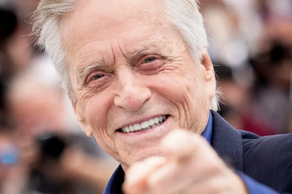 Uśmiechnięty Michael Douglas, który ma 79 lat, wskazuje palcem w obiektyw.
