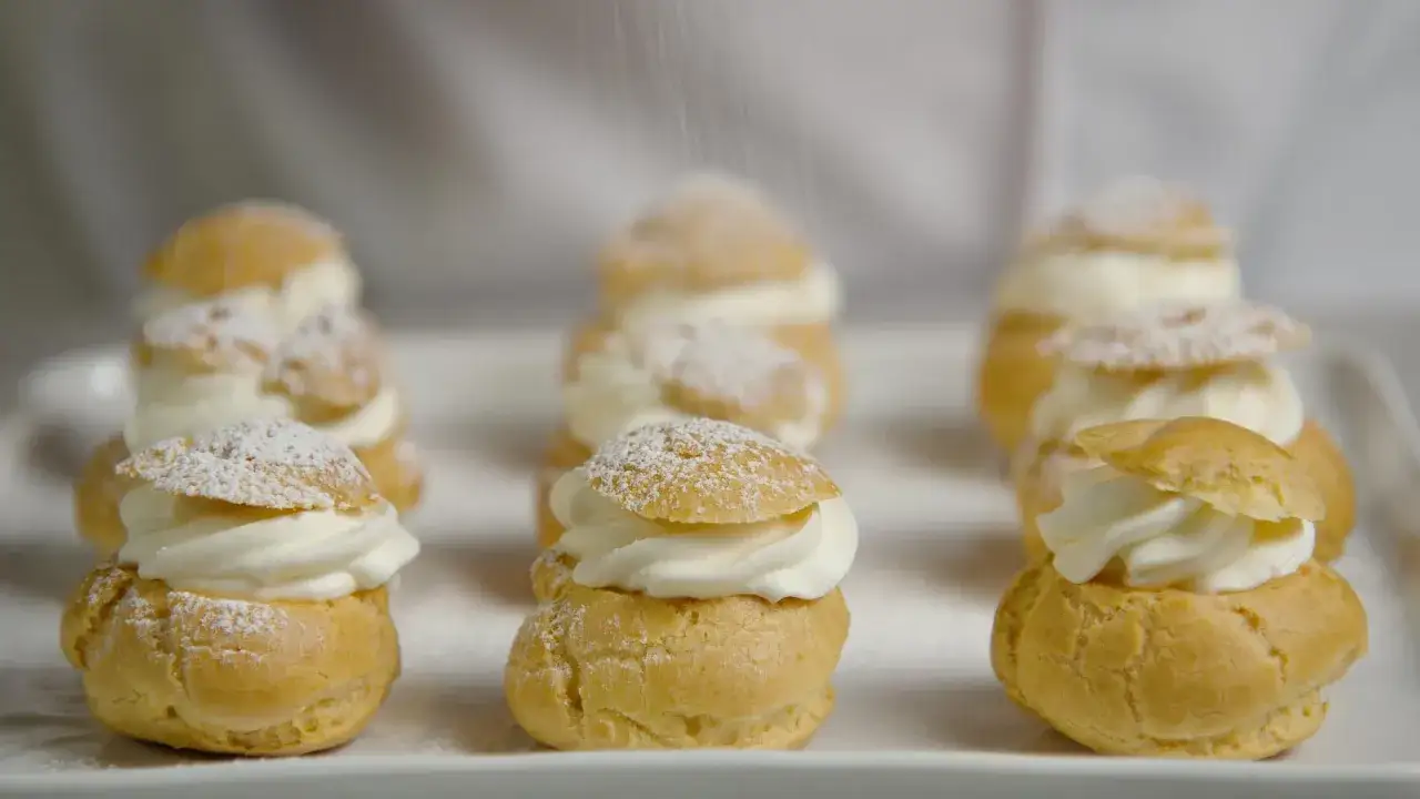 Petits choux garnis de crème fouettée, saupoudrés de sucre glace. La recette parfaite pour un dessert digne du Meilleur Pâtissier.