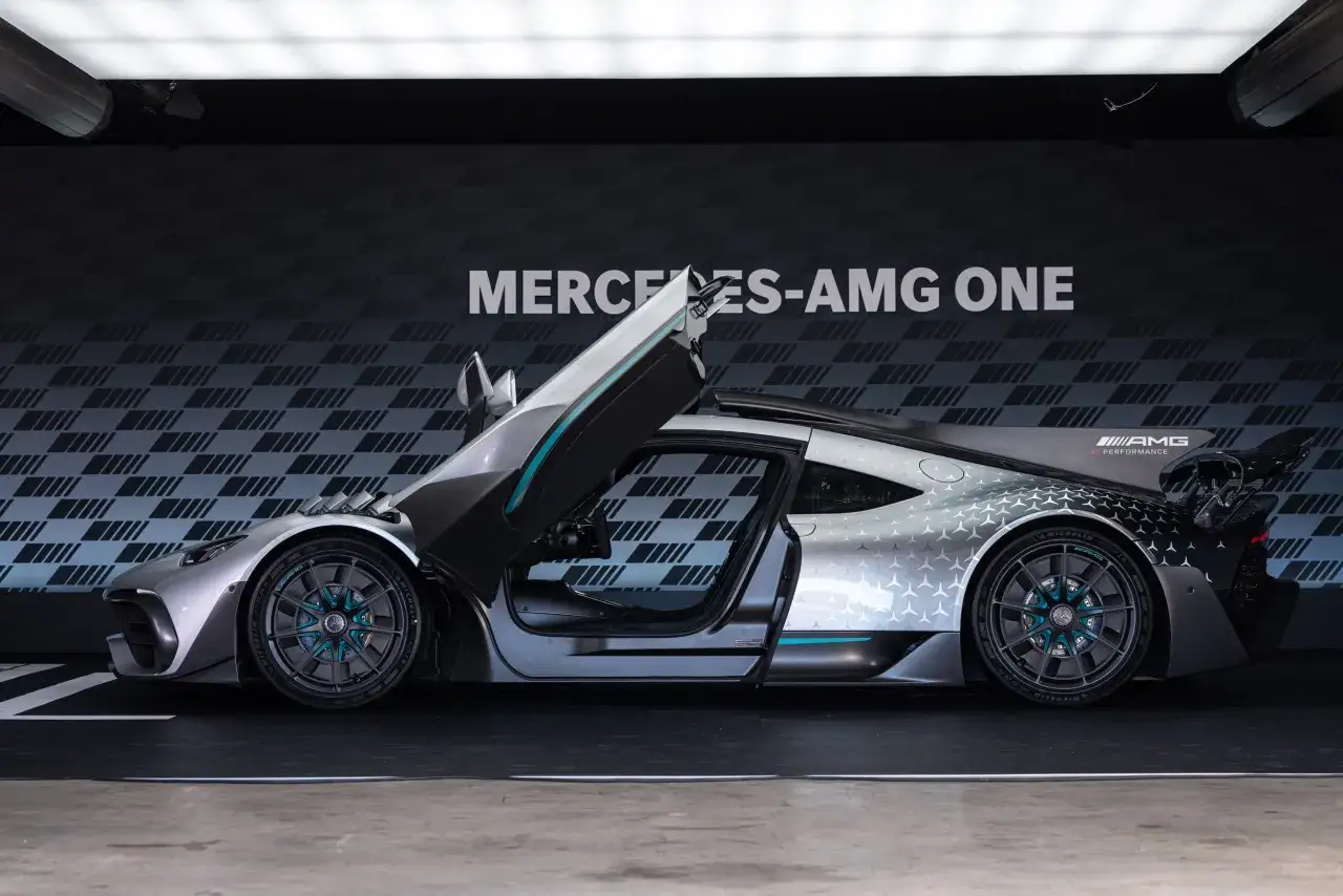 Srebrny Mercedes-AMG ONE z otwartymi drzwiami i maską, prezentujący swoje futurystyczne linie i sportowy charakter.