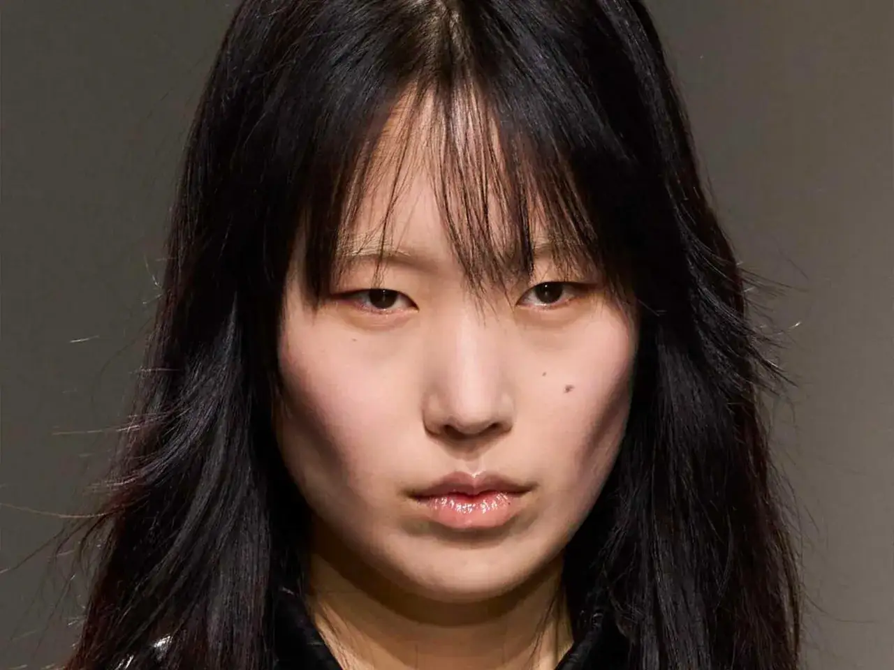 Rostro de modelo con cabello negro y flequillo desordenado, un corte **hush cut** que enmarca su rostro.