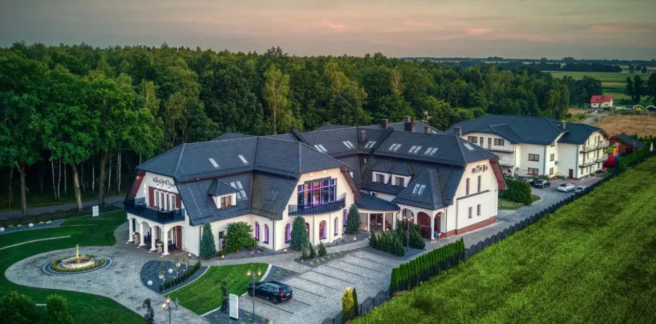 Elegancki biały dom restauracja hotel&spa otoczony zielenią. Zaprasza na wypoczynek i relaks.