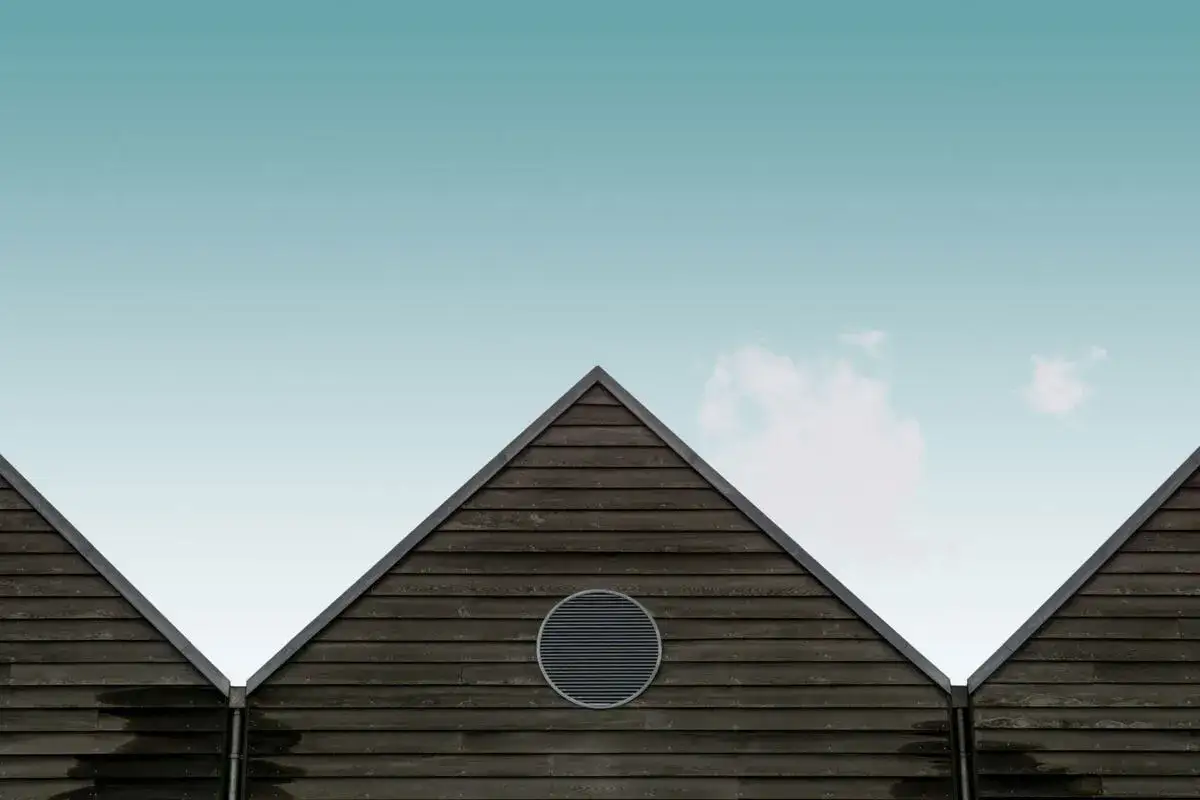 Drewniane ściany szczytowe z okrągłym otworem wentylacyjnym tworzą geometryczny dach bezokapowy.