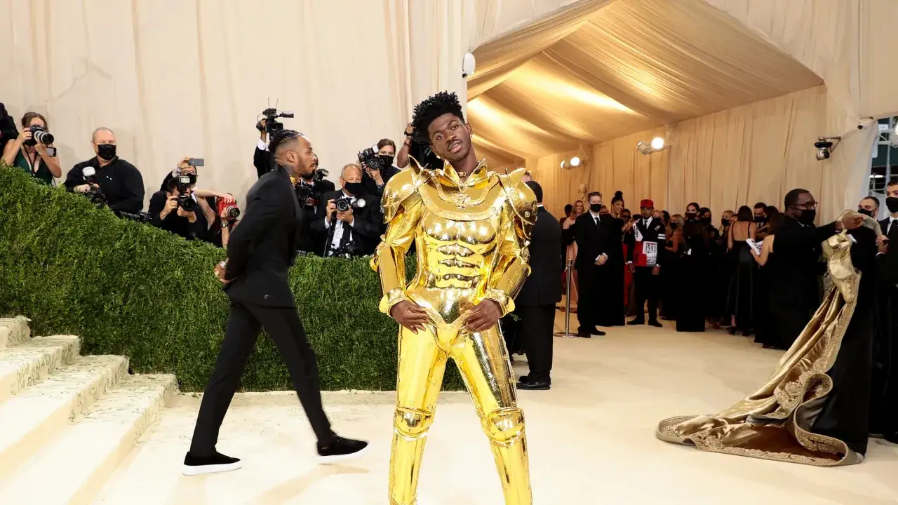 Lil Nas X, un caballero dorado, posa en la alfombra de la Met Gala, rodeado de fotógrafos y admiradores.