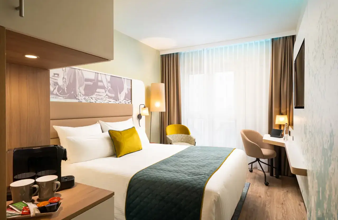 Modern Hotelzimmer mit Bett, Schreibtisch und Kaffeemaschine.