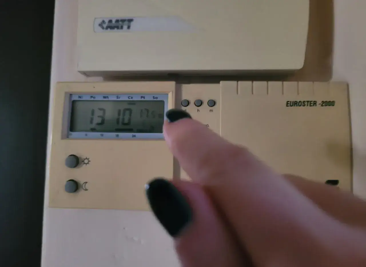 Dłoń z czarnym lakierem na paznokciach dotyka termostatu, sterowanie piecem gazowym. Na wyświetlaczu 13:10 i 17.5°C.