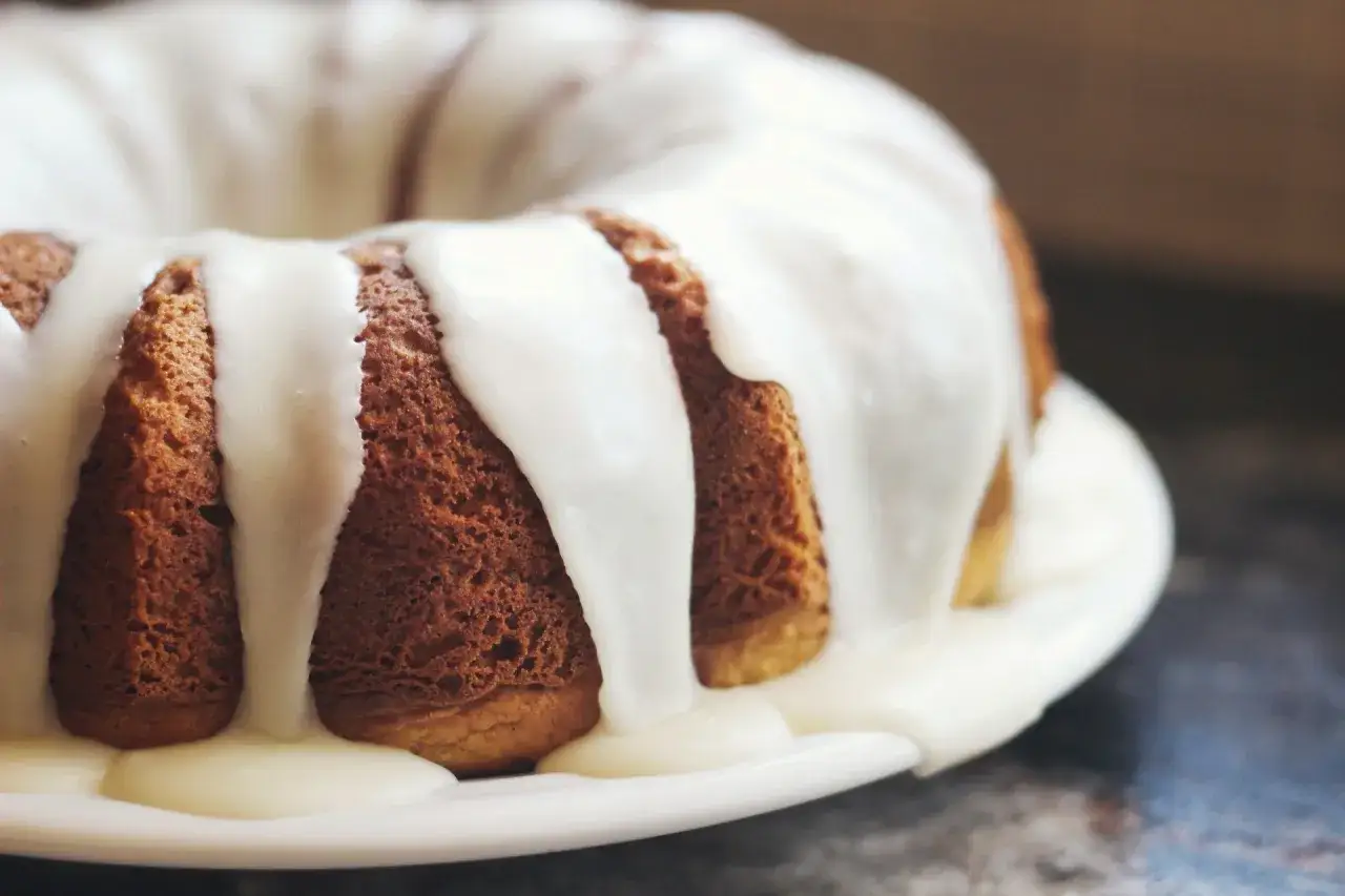 Gâteau moulé, doré, nappé d'un glaçage blanc crémeux. Une invitation à découvrir comment faire du fondant blanc.