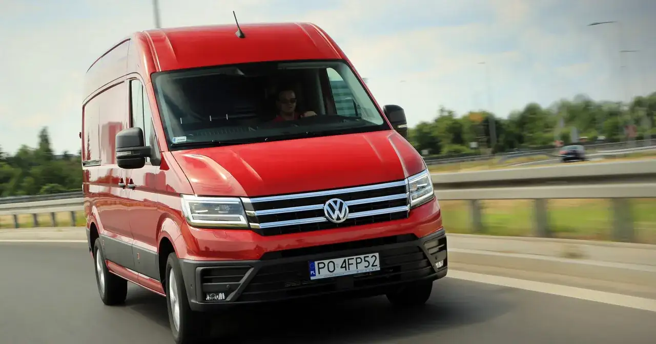Czerwony VW Crafter pędzi autostradą. Kierowca w okularach prowadzi auto, które jest w ruchu.