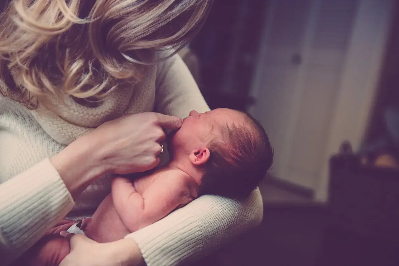 Delikatne dotknięcie palcem ust noworodka, gdy mama próbuje poradzić sobie z kryzysem laktacyjnym.