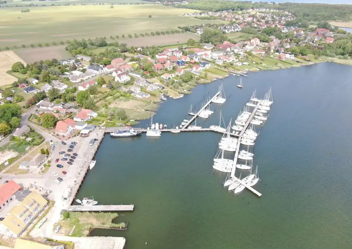 Breege Hafen: Viele Segelboote liegen im Hafen von Breege, umgeben von Häusern und grünen Feldern.