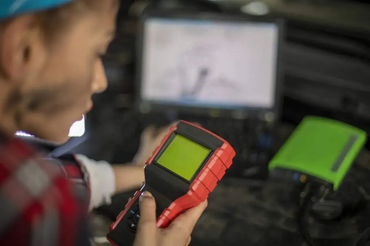 Mechanik z urządzeniem diagnostycznym i laptopem.