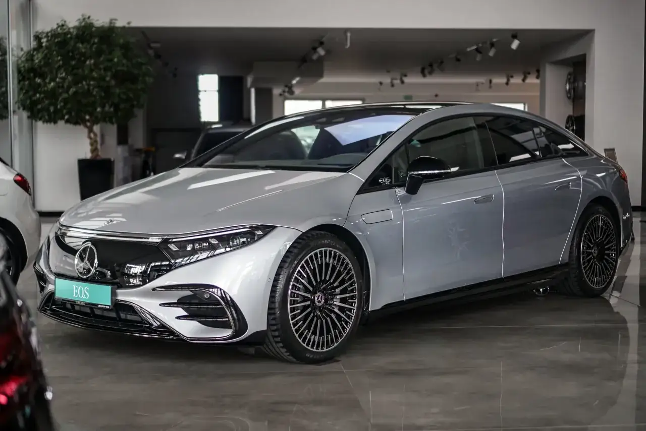 Srebrny Mercedes EQE, lśniący w salonie, z eleganckimi felgami i nowoczesnym designem.
