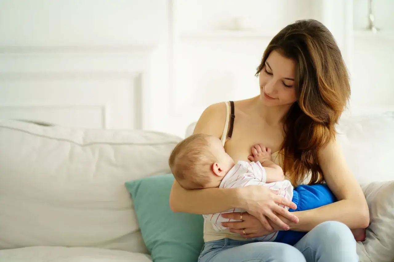 Ciepła chwila karmienia piersią. Mama z miłością patrzy na swoje dziecko, wspierając naturalną laktację.