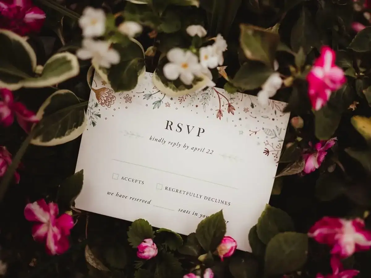 Karta RSVP z kwiatowym wzorem wśród zieleni i różowych kwiatów.