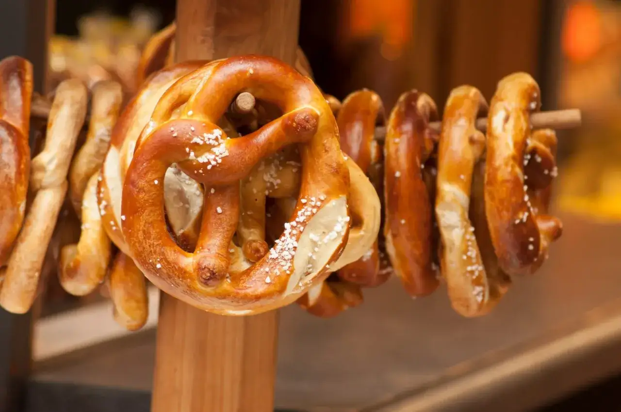 Des bretzels dorés, saupoudrés de gros sel, sont suspendus sur un support en bois. Ces spécialités lorraines invitent à la dégustation.