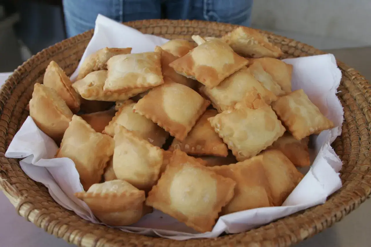 Un panier rempli de beignets dorés, une spécialité des Hautes-Alpes, prêts à être dégustés.
