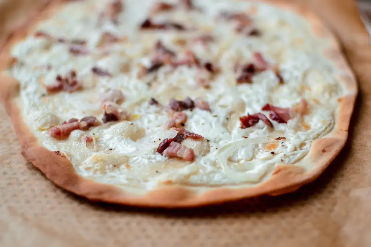Flamenkuche maison, une recette facile pour un repas gourmand. Pâte fine, crème, lardons et oignons pour une tarte flambée parfaite.