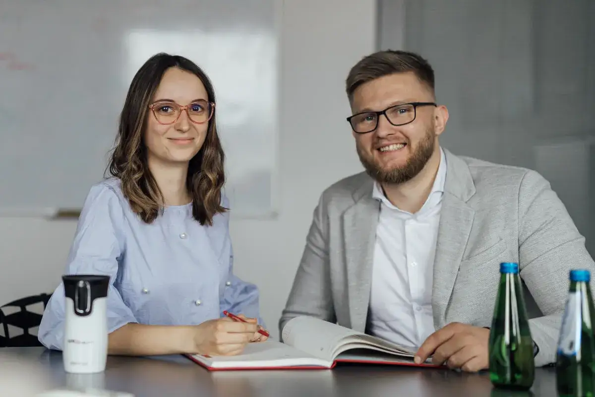 Uśmiechnięci pracownicy omawiają zatrudnienie osoby niepełnosprawnej i ulgi we wpłatach na PFRON.