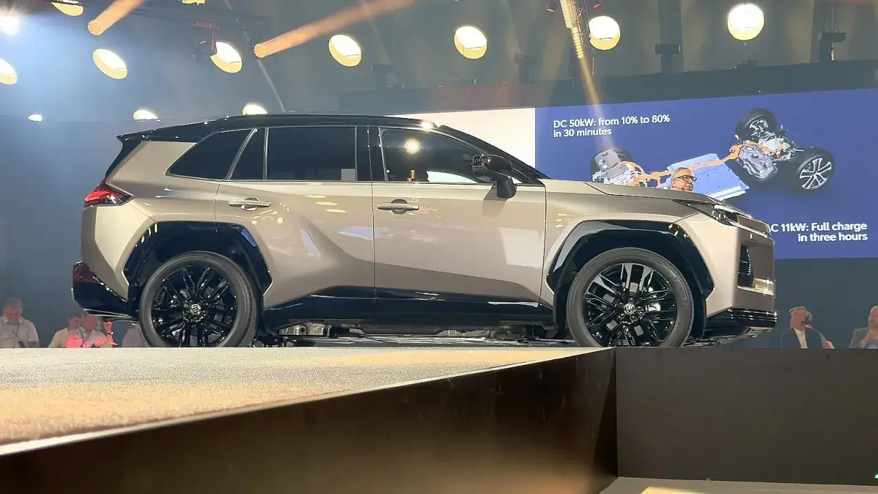 Nowa RAV4 prezentowana na scenie, z ekranem pokazującym dane ładowania.