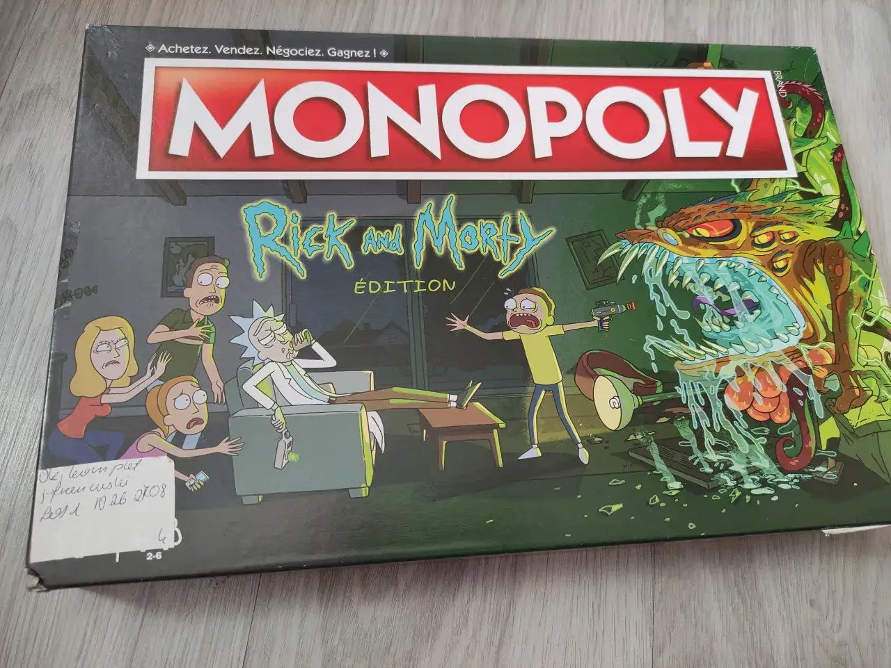 Pudełko gry Monopoly z Rickiem i Morty'm. Rodzina w panice, Rick relaksuje się z butelką, a potwór atakuje.