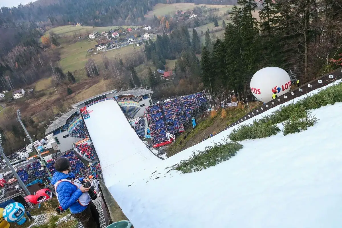 Widok z góry na skocznię narciarską podczas Pucharu Świata w Wiśle. Tłumy kibiców na trybunach, wielki balon LOTOS.