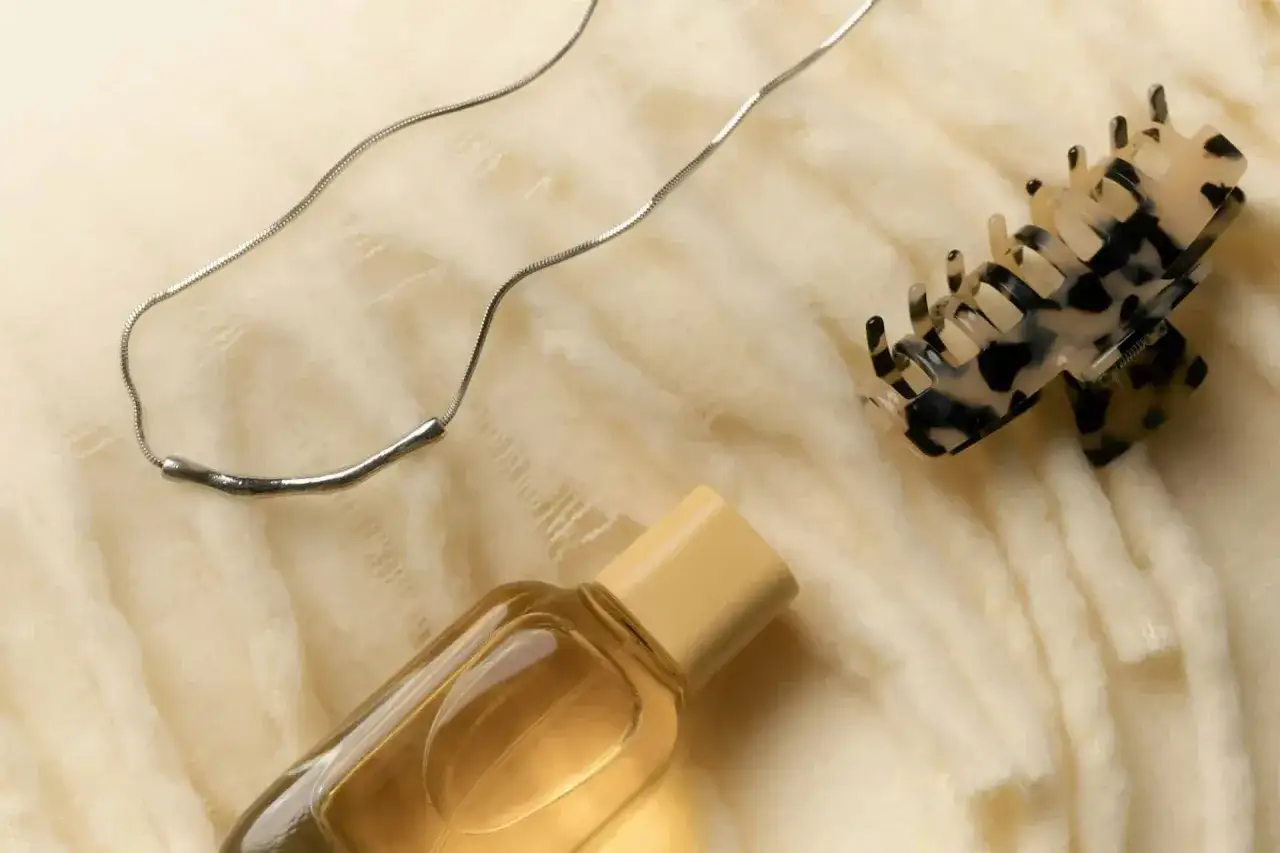 Perfumy w bagażu rejestrowanym? Tak, ale z głową. Elegancka biżuteria, spinki do włosów i buteleczka perfum na miękkim tle.