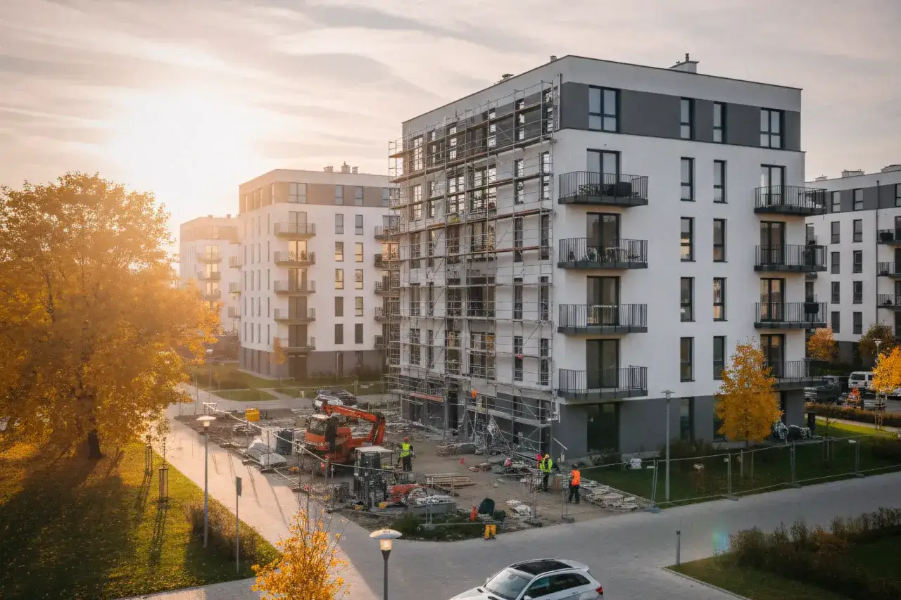 Budowa osiedla, prace budowlane i jesienne drzewa. To etap zakupu mieszkania od dewelopera krok po kroku.